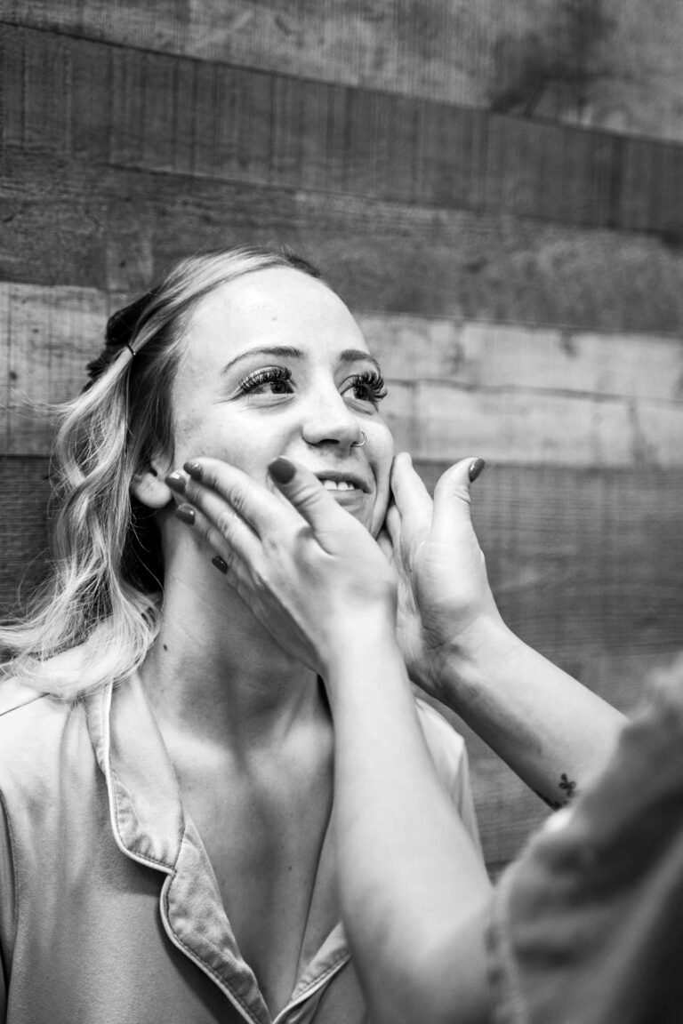 Black and white portrait of Leslie smiling during makeup preparation.