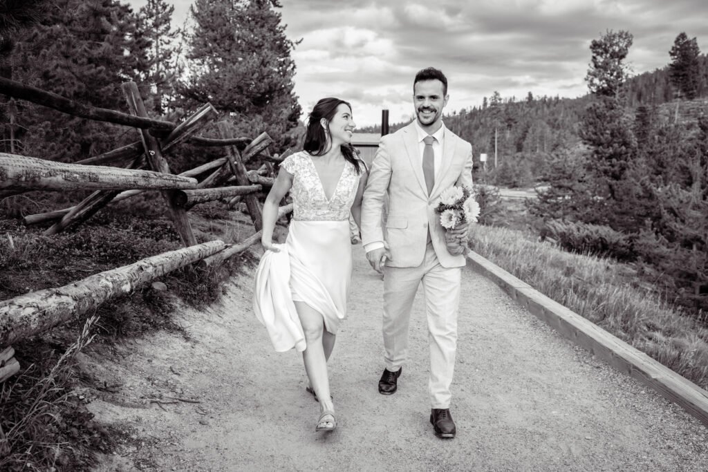 Black and white photograph of Alex and Nicole walking hand in hand along a mountain path.