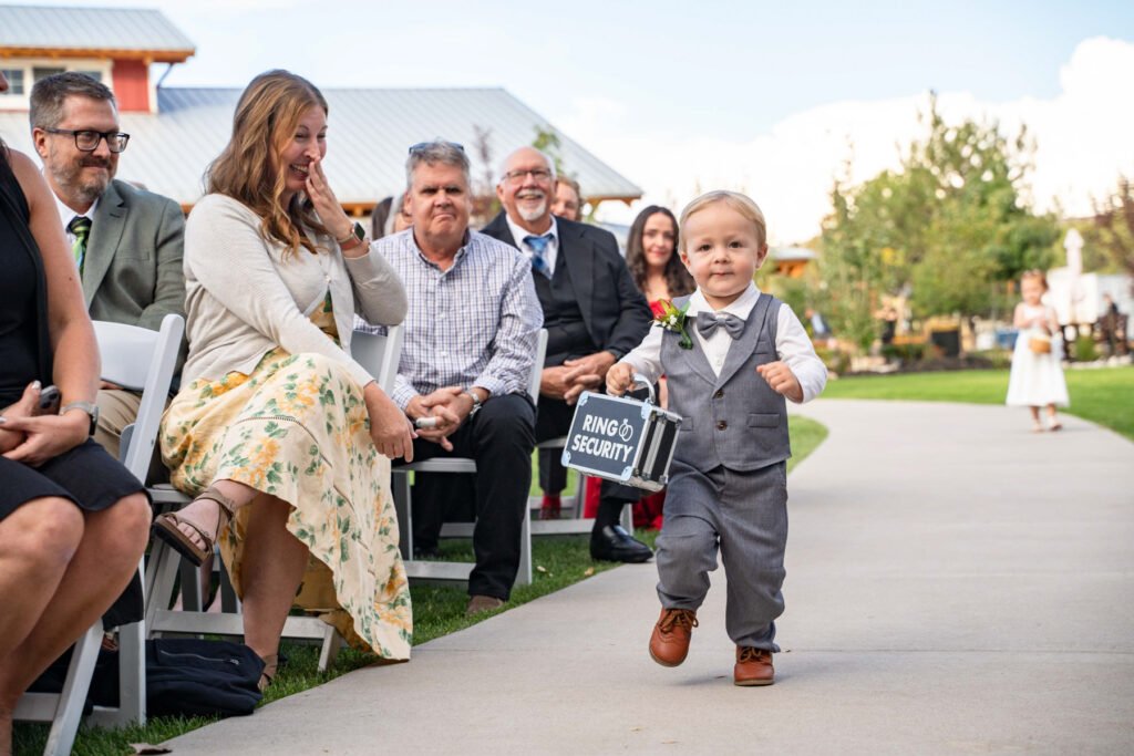 A young ring bearer walks down the aisle carrying a Ring Security case.