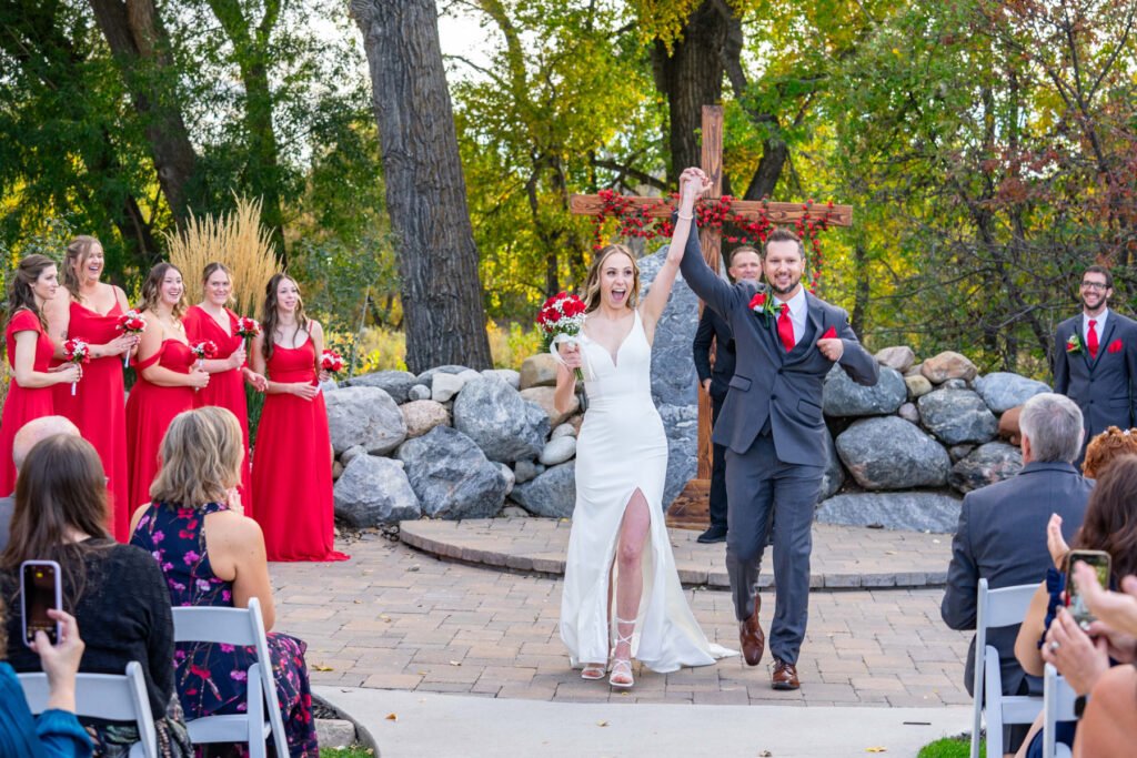 Leslie and Michael celebrate with raised arms after their wedding ceremony.